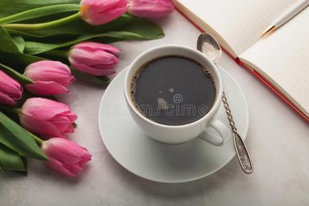 女人工作的书桌和咖啡豆马克杯,笔记簿和春季郁金香flores花