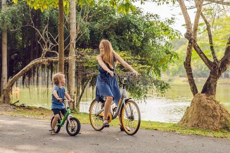 幸福的家庭是（be的三单形式骑马自行车在户外和微笑的.妈妈向一自行车