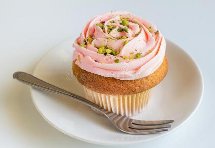粉红色的玫瑰旋转甜奶油酱香子兰杯子蛋糕向白色的后台