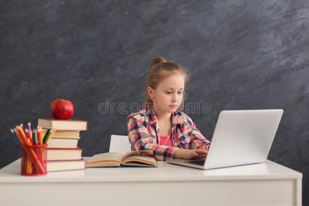 漂亮的小的女孩做家庭作业向便携式电脑