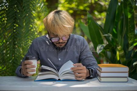 年幼的低到臀部的胡须男人喝饮料咖啡豆在期间阅读书采用英语字母表的第8个字母