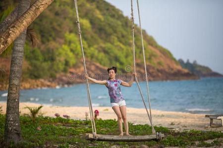 年幼的女人向指已提到的人木制的摆动向海海滩.