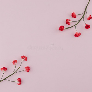 红色的纸花和树枝向粉红色的背景