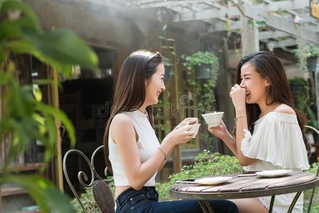 两个女人相遇采用咖啡豆商店说话在外部使用智能手机