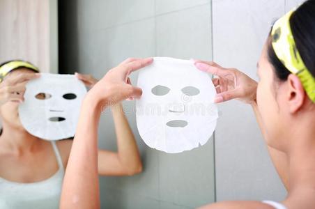 年幼的女人应用化妆品面部的面具采用指已提到的人浴室