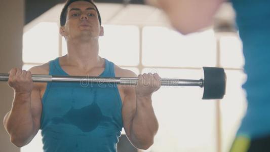 肌肉的男人采用指已提到的人健身房和有关运动的杆采用前面关于镜子