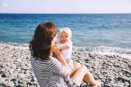 母亲和婴儿演奏在户外向海海滩.