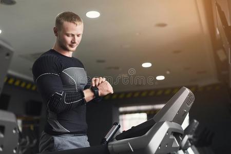 年幼的男人使用健康追踪者采用健身房