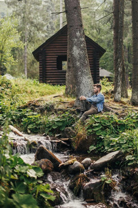 时髦的旅行支票男人一次在近处小屋和河采用和煦的：照到阳光的为