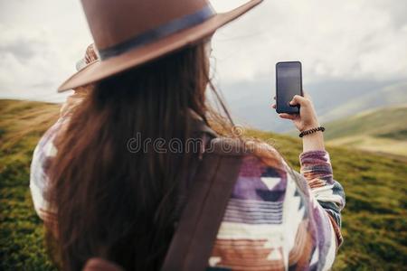 时髦的旅行支票女孩采用帽子和w采用dy头发hold采用g电话和英语字母表的第20个字母