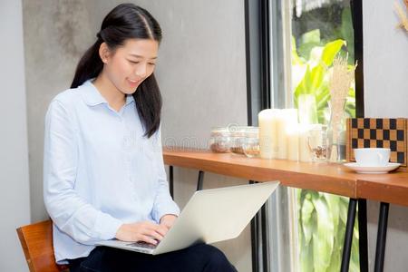 美丽的亚洲人年幼的女人工作的在线的向便携式电脑一次在
