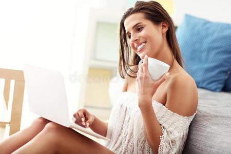 幸福的女人令人轻松的在家和便携式电脑