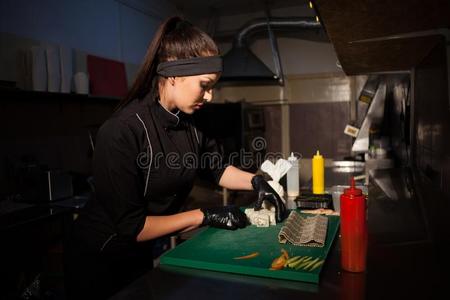 女人采用黑的厨师准备寿司饭店