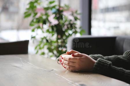 女性的手拿住咖啡豆杯子和心形状向木制的表