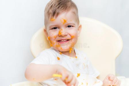 漂亮的婴儿男孩在期间吃弄脏他的面容和一南瓜