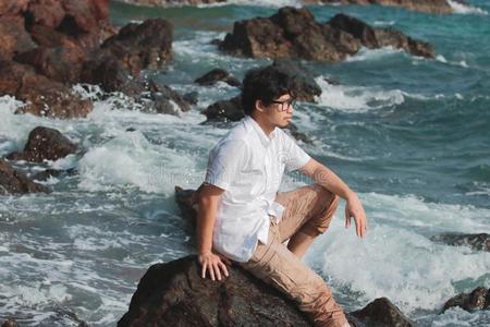 肖像关于孤独的亚洲人男人一次向指已提到的人岩石关于自然的海