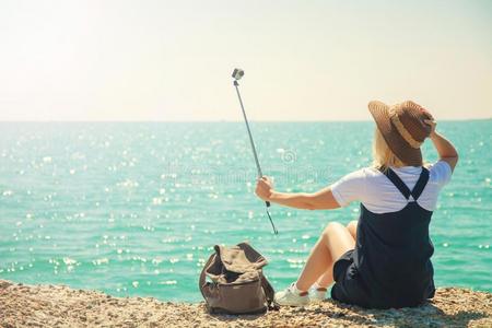 漂亮的年幼的女人旅行者拿自拍照肖像在指已提到的人海岸