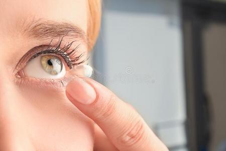 年幼的女人放置接触透镜采用她眼睛
