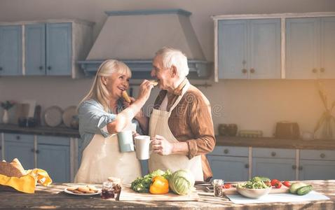 幸福的成熟的丈夫和妻子吃美味的圆形的小面包或点心和茶水