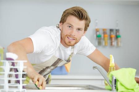 男人清洁厨房家具在旁边黄色的布