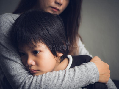 特写镜头悲哀的小的男孩存在热烈地拥抱在旁边他的母亲在家.