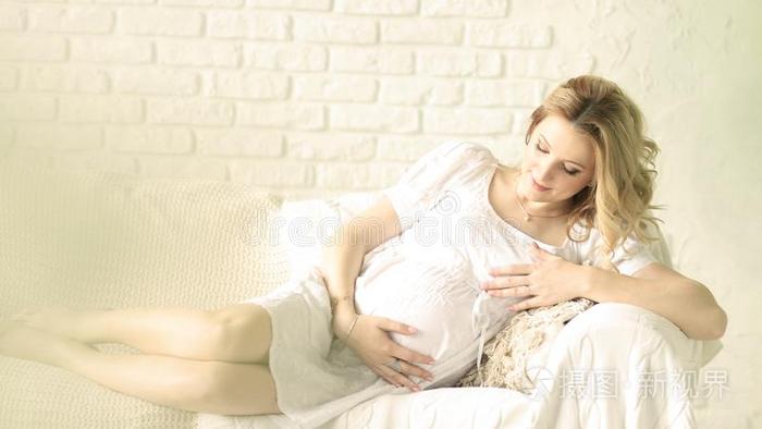 幸福的怀孕的女人一次向沙发在家