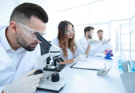 男性的实验室技术人员有样子的在样品采用指已提到的人显微镜