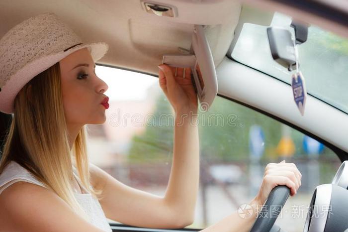 思想不集中的女人操纵她汽车有样子的采用镜子
