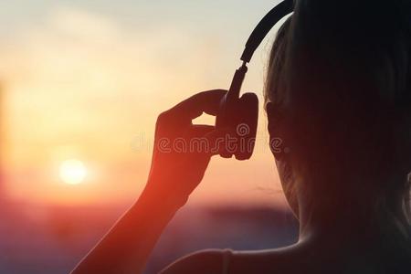 女孩采用耳机listen采用g向音乐采用指已提到的人城市在日落