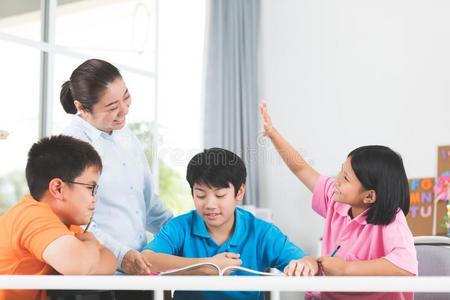 年幼的亚洲人教师问问题年幼的小孩采用教室.
