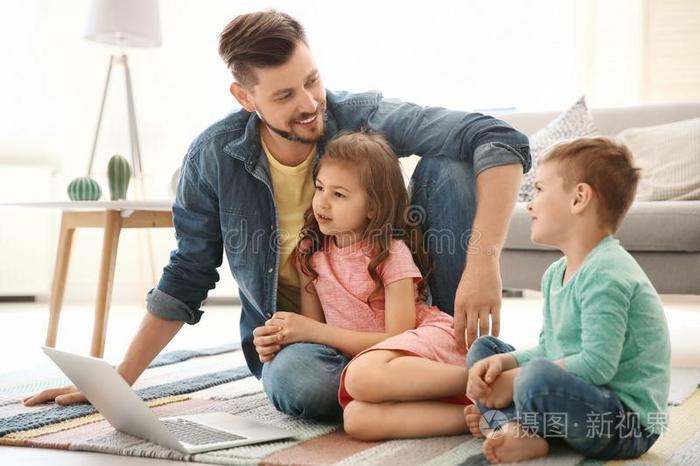 年幼的男人使用便携式电脑和孩子们在家