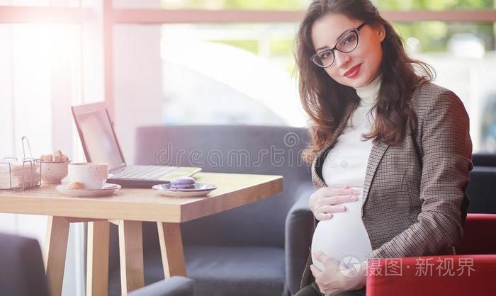 怀孕的女人工作的向计算机采用咖啡馆