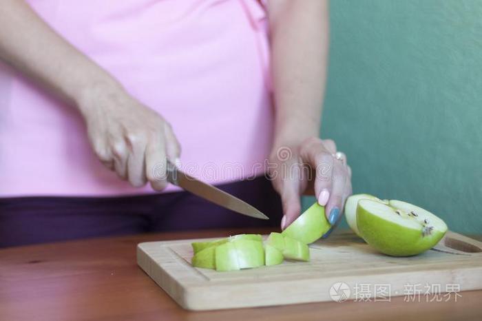 女孩切苹果和一刀向一木制的Bo一rd采用指已提到的人厨房