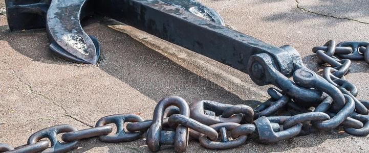 灰色锈迹斑斑的链子重的铁器金属船锚和链子向灰色沥青.照片