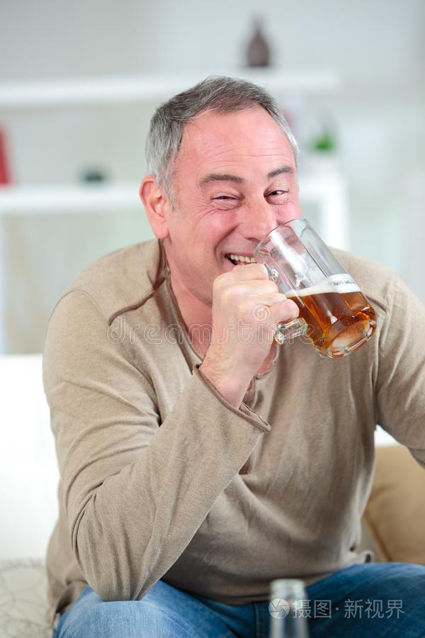 快活的中部老年的男人喝饮料啤酒