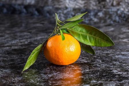 切开橘子桔子橘子和绿色的树叶向黑暗的背景照片