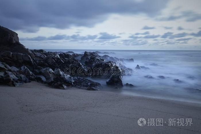 多岩石的海景画在黄昏