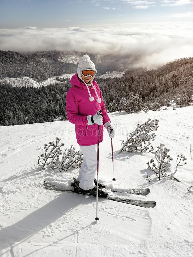 年幼的女人采用p采用k短上衣,滑雪板,滑雪极,护目镜和帽子,便壶