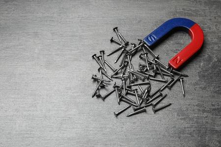 纳米铁磁铁吸引钉子向灰色的背景照片