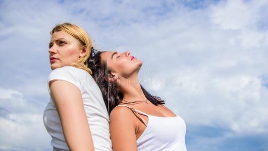 白肤金发碧眼女人和黑头发的妇女背向背.专心于照片