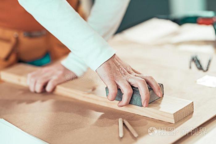 女性的木工用手地砂纸打磨木制的木板