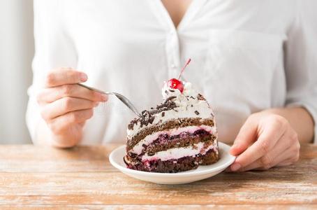 女人吃块关于层蛋糕和樱桃照片