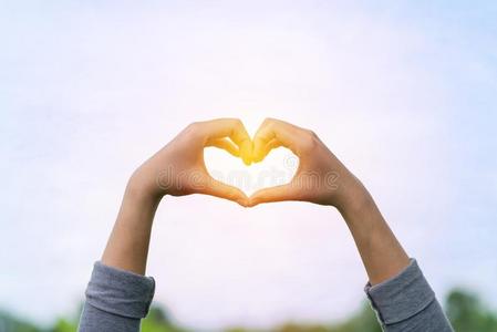 爱心-合适的手手势,爱浪漫的情侣在日落打手势用手指一颗心的爱年轻