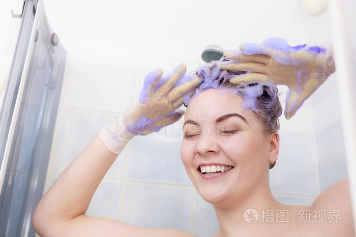 女人应用调色剂洗发剂向她头发