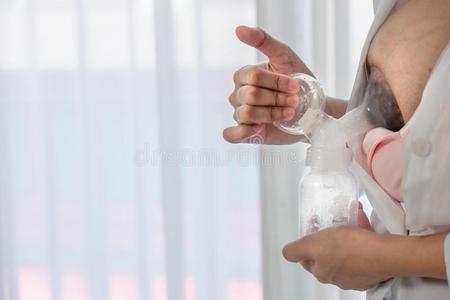 婴儿母乳喂养关母亲使用乳房泵向收集乳房-奶为她婴儿照片