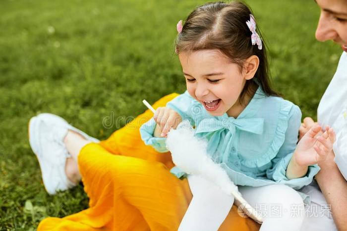 欢乐的小的女孩吃棉糖果和她mot她一次