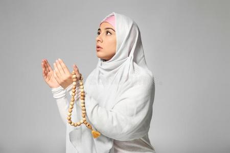 年幼的穆斯林女人祈祷向光背景照片
