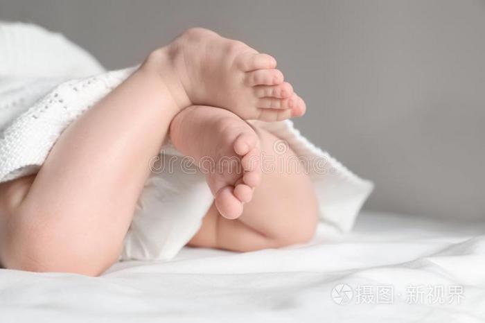 小的婴儿和漂亮的脚说谎向床,特写镜头