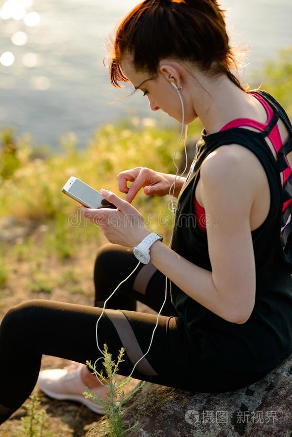 年幼的女人赛跑者使用智能手机和收听的向音乐在USSR苏联