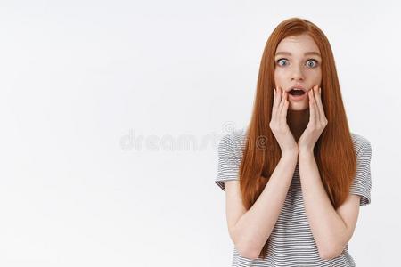 惊愕的无言的年幼的胆小的漂亮的红发的人女孩落下下巴触摸照片